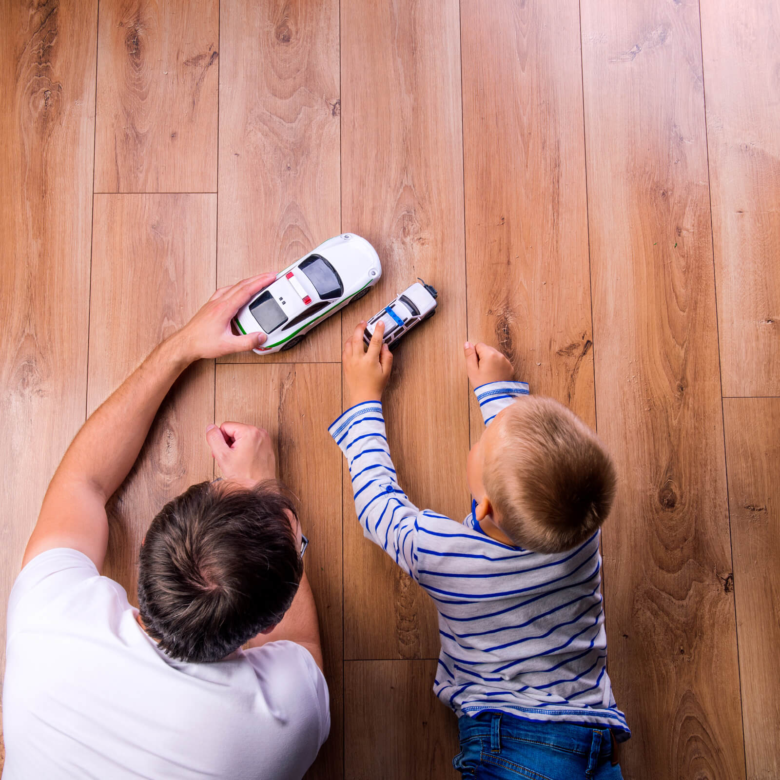 Man and boy with toy cars on hardwood floor | Allied Flooring & Paint